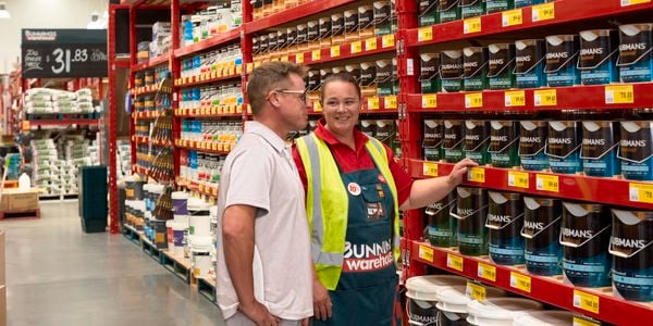 <p>Team member showing man in white tee the paint range bunnings offer</p>