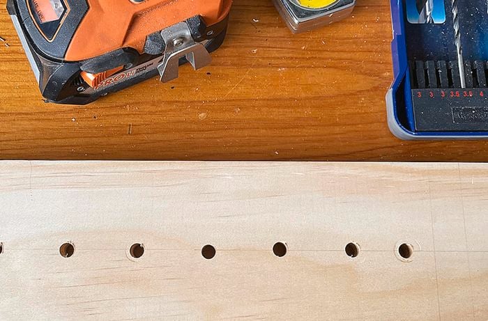 A piece of wood with a drill and drill bits