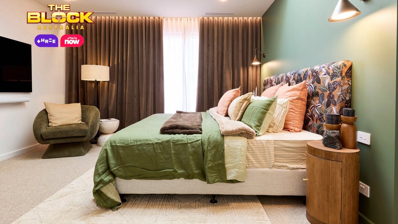 Bedroom with green feature wall, patterned headboard, and layered bedding.