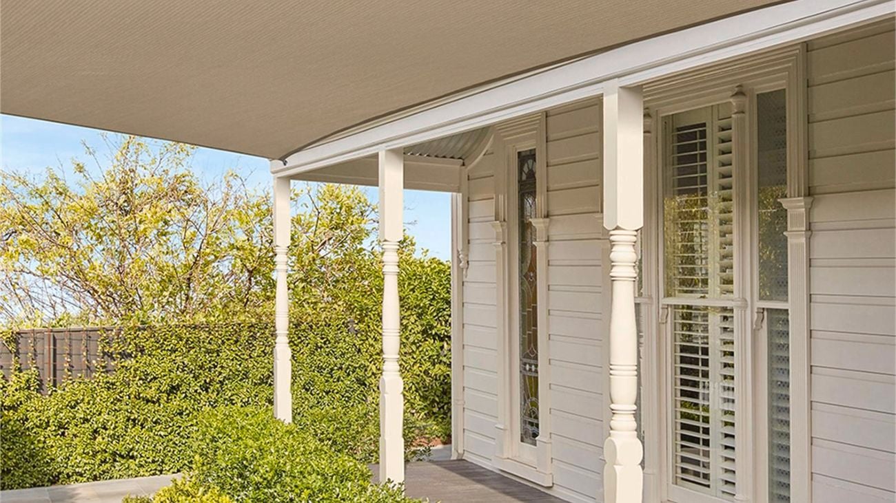 A backyard porch with a large Beech-coloured Coolaroo shade sail covering the garden.