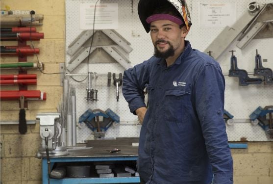 Person standing in workshop with welding mask raised
