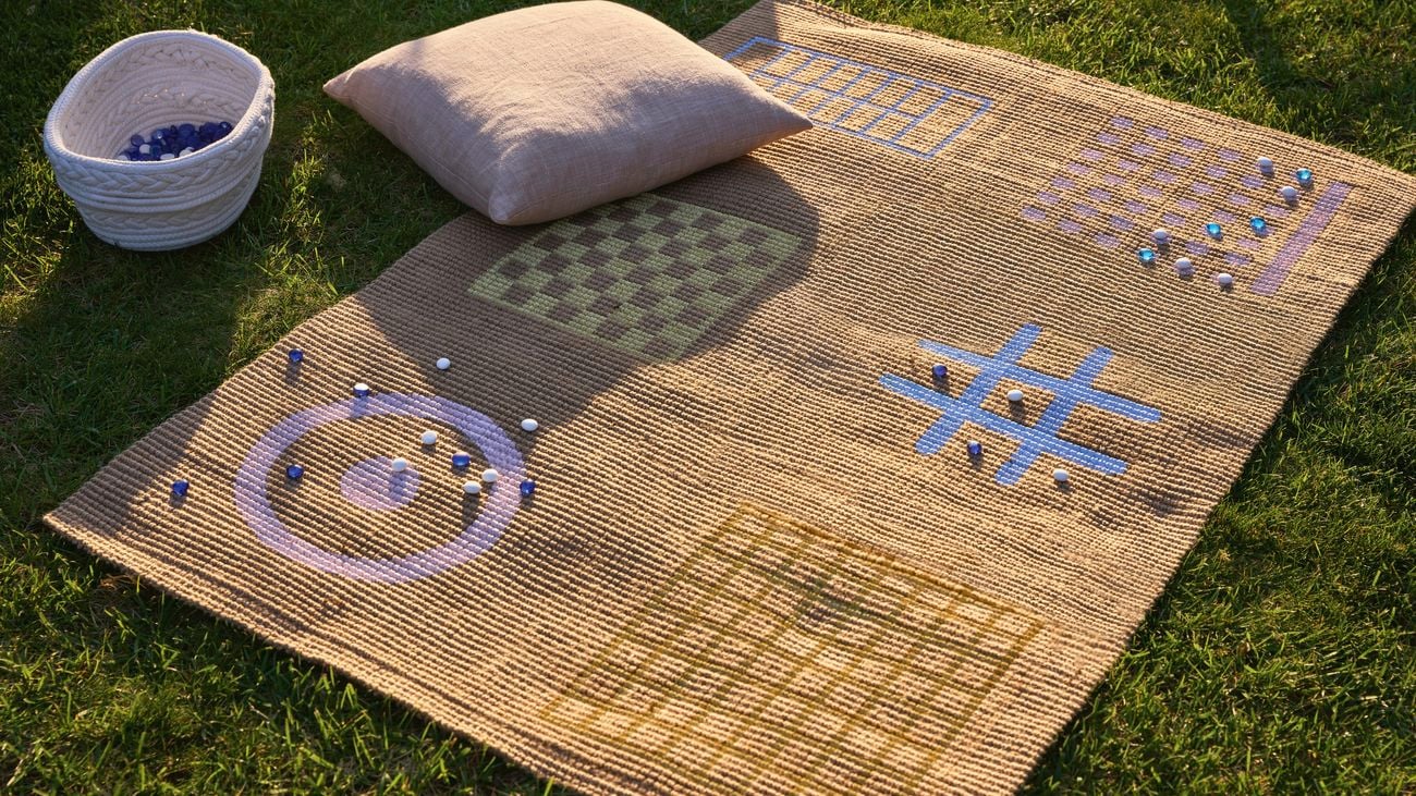 Kids playmat set up outside with cushion and game accessories.