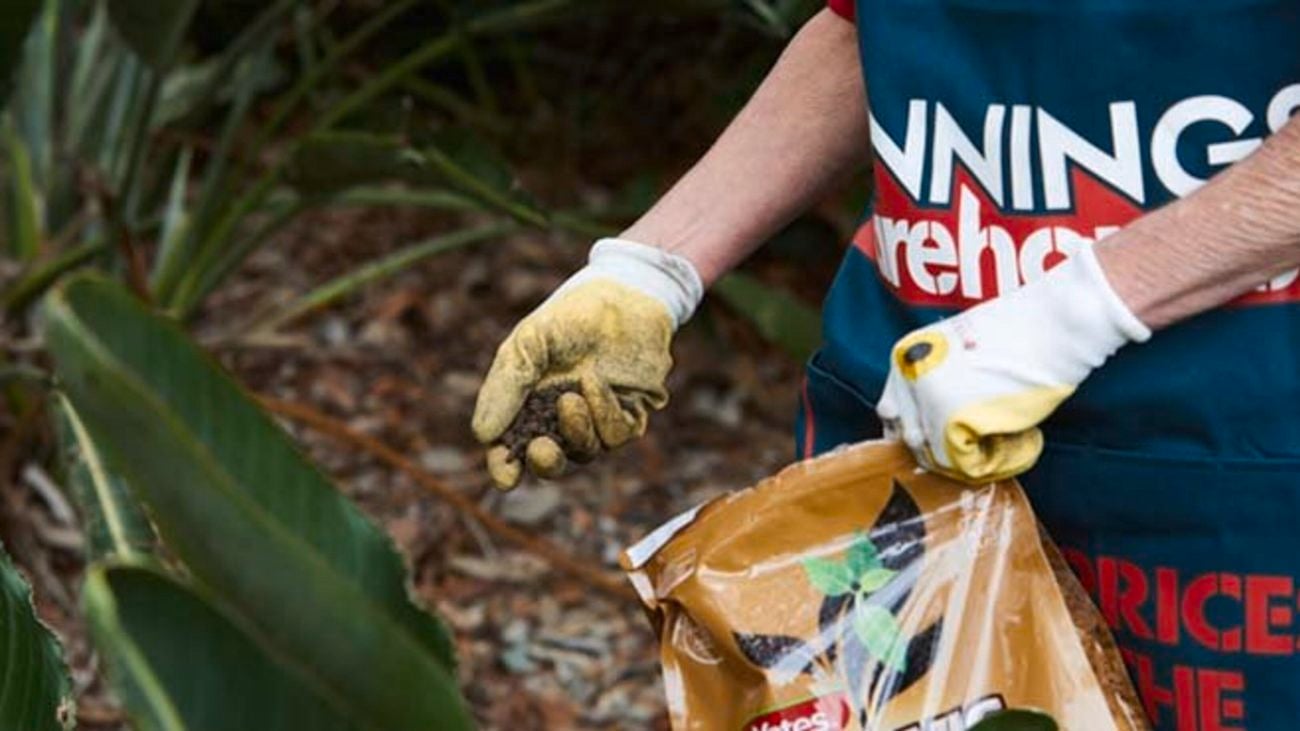 Person placing soil in garden.