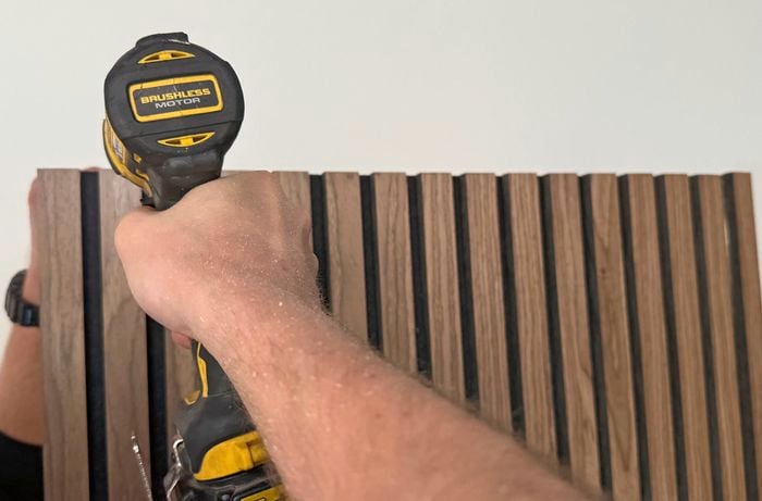Close up of a drill driving a screw into timber cladding