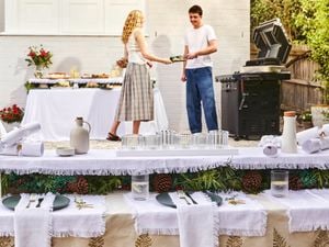 A Christmas table with white bon bons and place settings and people in the back ground