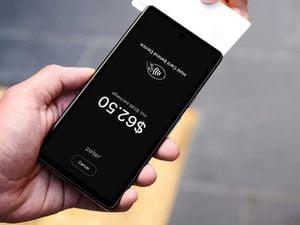 A person holding a card to a smart phone to make payment