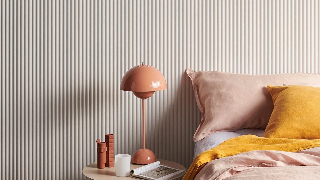 Pink and white Laminex wall in a bedroom with bed and side table.