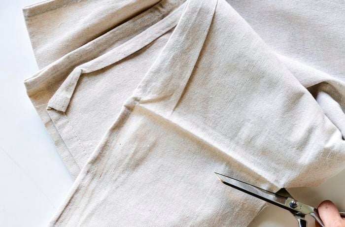 A woman cuts a drop sheet with scissors