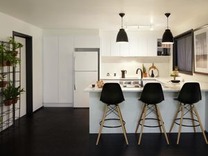 White kitchen with black pendant lamps and three bar stools