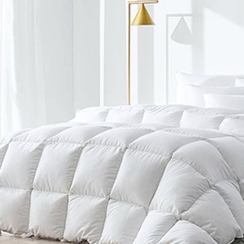 Plush white quilt on a modern bed with soft lighting.