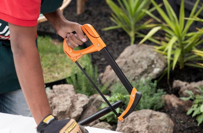A saw being used to cut a length of metal pipe