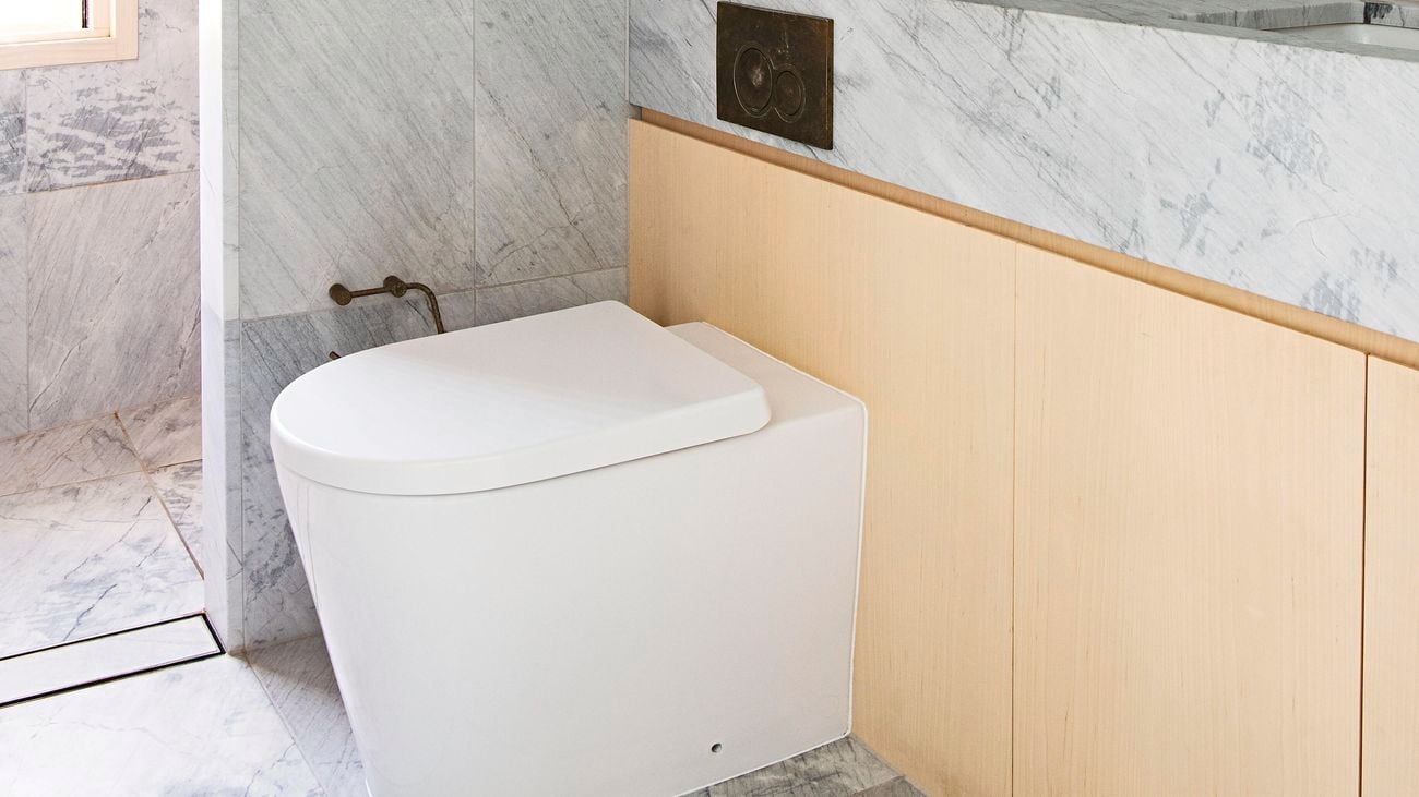 Modern bathroom with marble tiles featuring a toilet, shower alcove and countertop