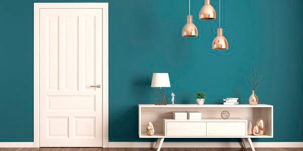 White door against a teal blue wall, to the right of the shot. There is a small cabinet to the right.