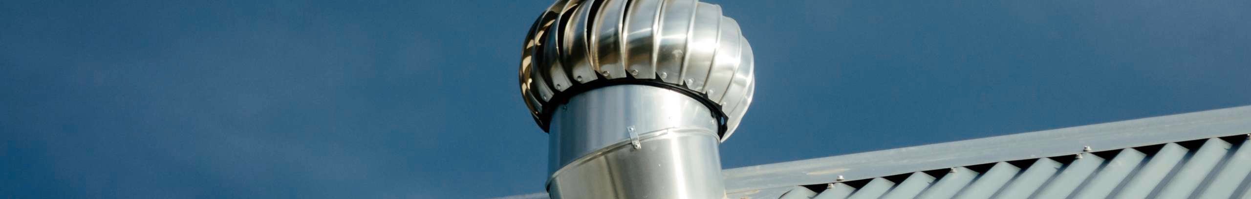 Close up shot of a roof vent on a tin roof with a deep blue sky in the background