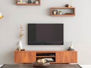 TV on wall in lounge room. The room has a grey colour scheme with a touch of dark toned wood. There is a TV on a wall bracket at the centre of the shot.