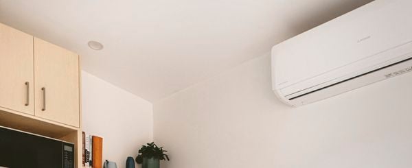 Kitchen with a wooden table and chairs and a split system air conditioner on the wall.