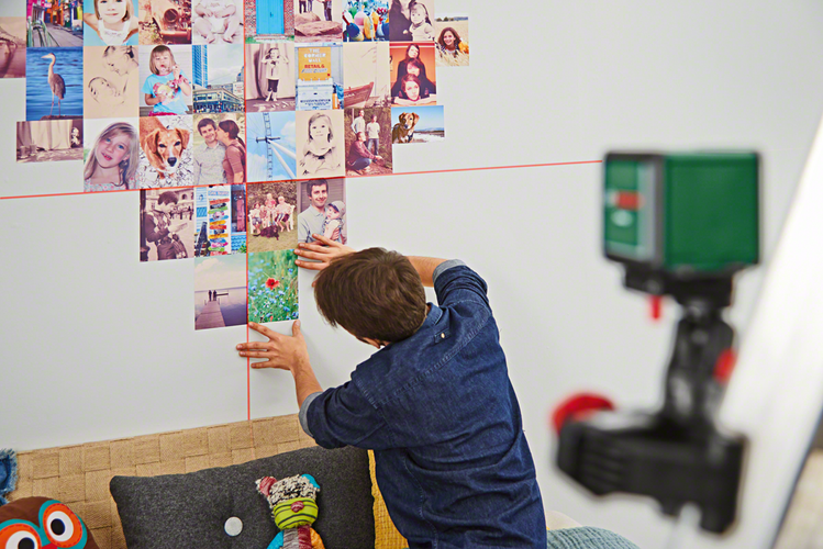 Person using laser level to hang pictures