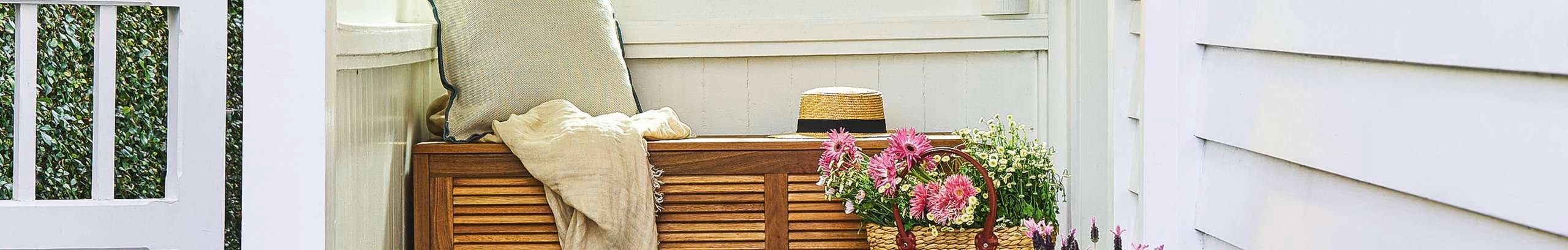 Timber storage bench seat with cushion and basket of flowers.