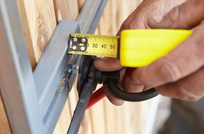 Person measuring the spindle of a latch for a gate