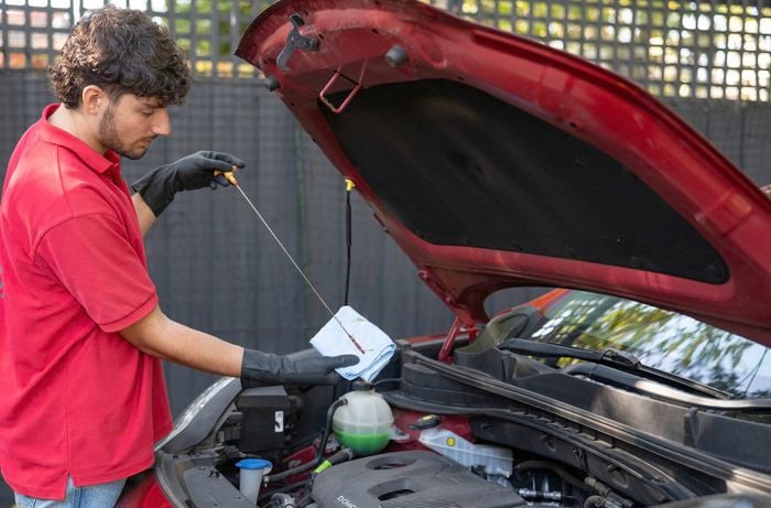 A Bunnings Team Member is checking and wiping the dipstick with a cloth  to clears off any oil the splashed around while the engine was running.