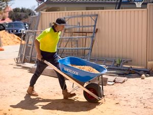 tradie wheeling a wheelbarrow on work site