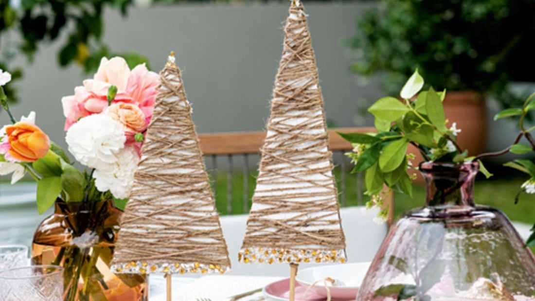 Cardboard Christmas trees on a decorated table with flowers in vases and tableware 