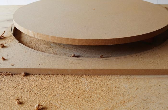 Circular tabletop being removed from timber cutout