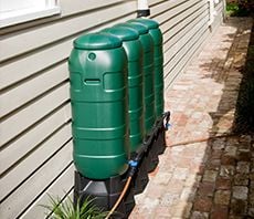 Four compost tumbler drums placed along the side of a house