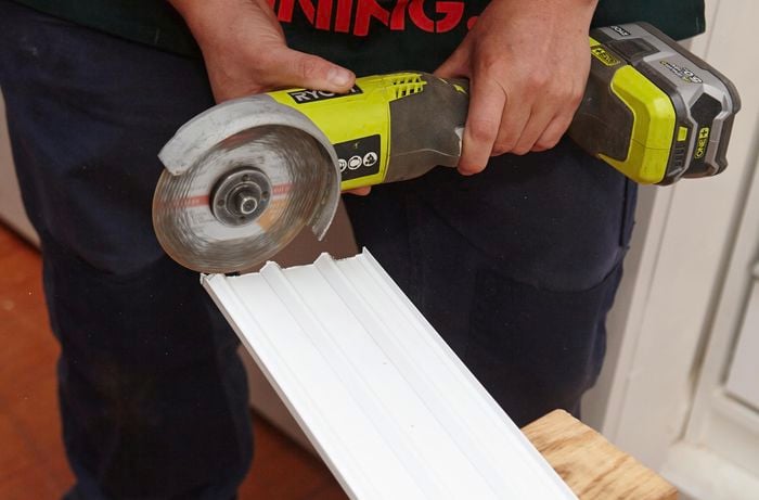 A person trimming a track with an angle grinder