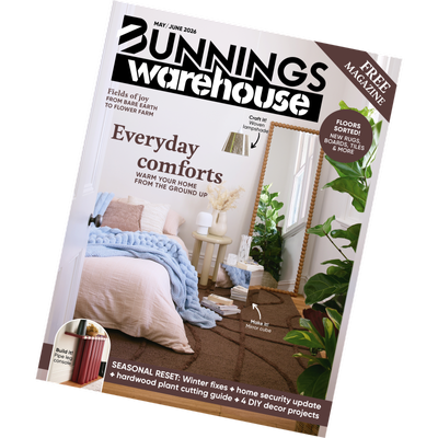 Tilted cover of the May/June 2026 Bunnings Warehouse magazine featuring a styled bedroom with layered bedding, indoor plants, and a headline reading ‘Everyday comforts’.