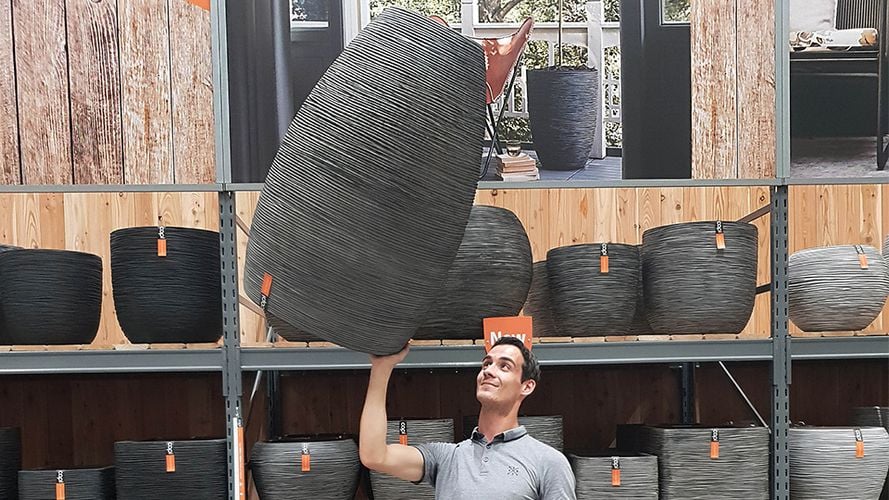 Man holding large pot for plants above his head