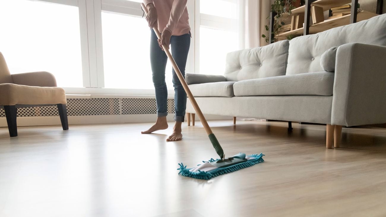Person in jeans uses a mop to mop hardwood floors