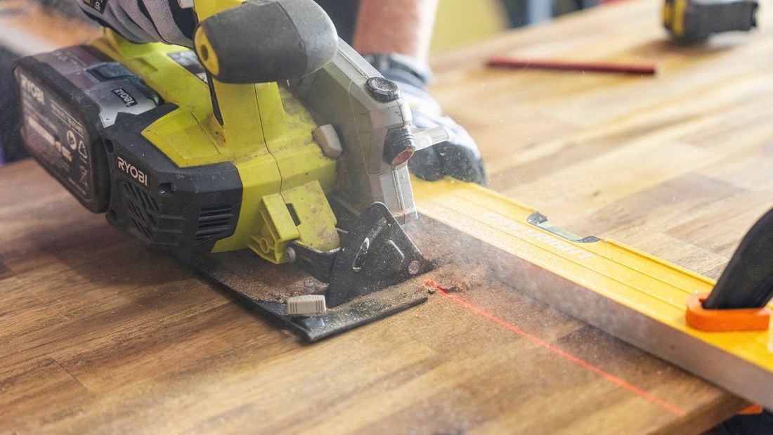 Close up of circular saw from a power tool kit cutting through timber with a laser line and spirit level.