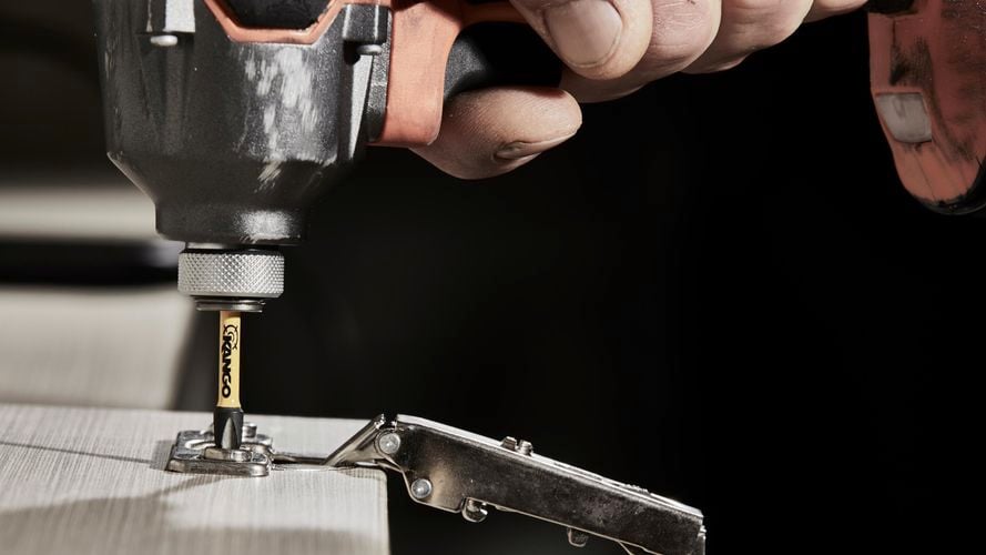 Drilling nail into hinge.