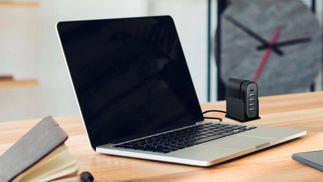 Laptop on a wooden desk with a charging hub aside