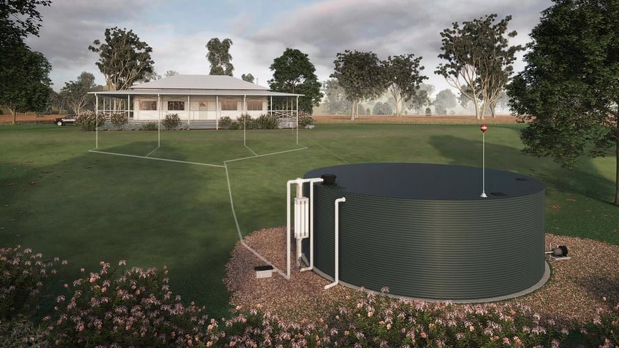The backyard of a rural house attached by underground downpipes to a water tank surrounded by shrubs and trees.