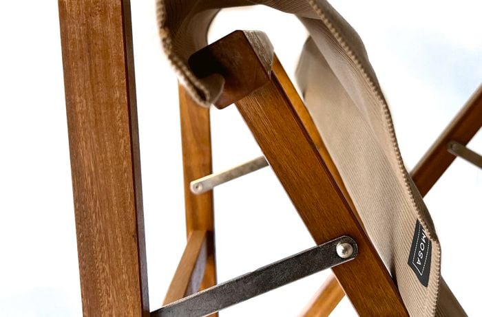 Close up of a hand holding a piece of fabric attached to the legs of a foldable chair