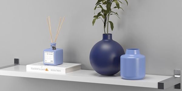 A floating shelf holding a blue ball vase and diffuser and book.