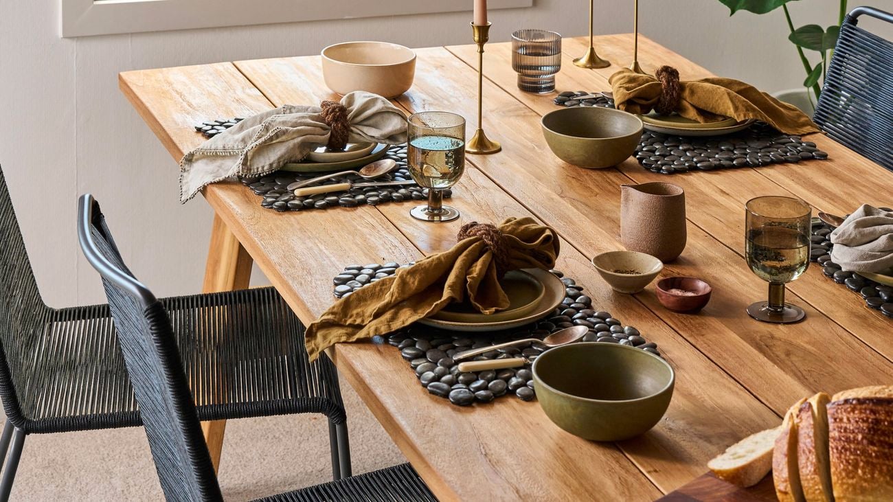 A black pebble placemat, with a rope napkin ring, napkin and plates