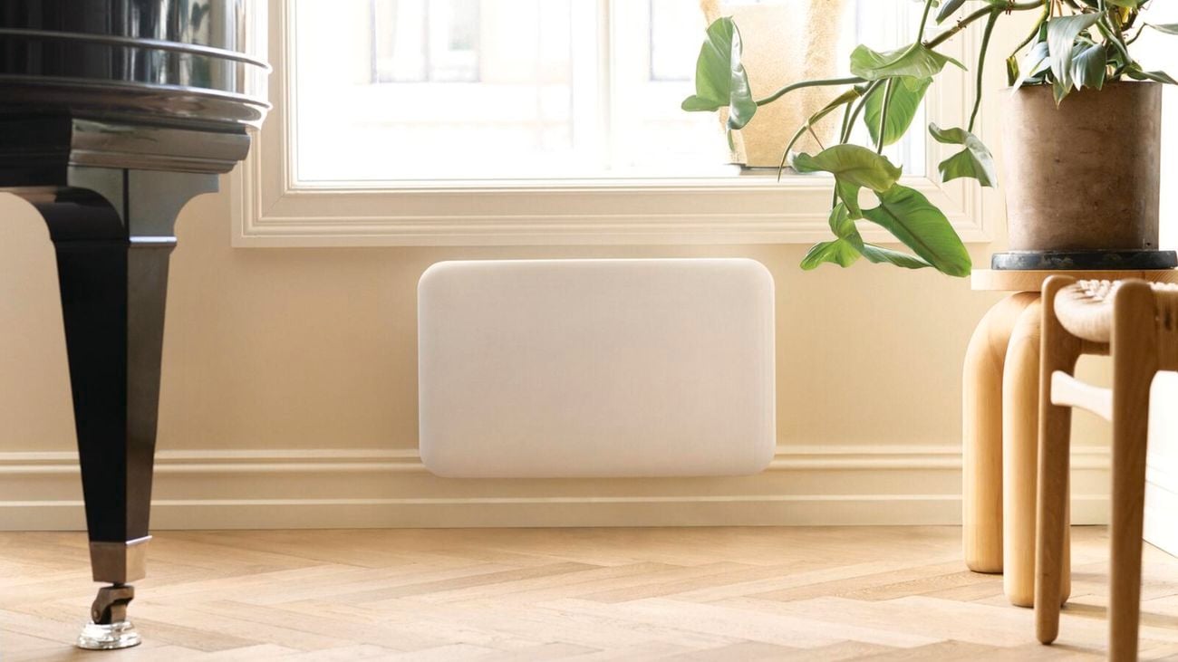 White panel heater mounted onto the bottom of a cream wall in a living room area]