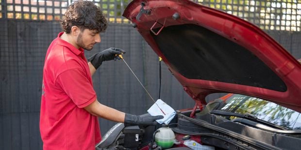 A Bunnings Team Member is checking and wiping the dipstick with a cloth  to clears off any oil the splashed around while the engine was running.