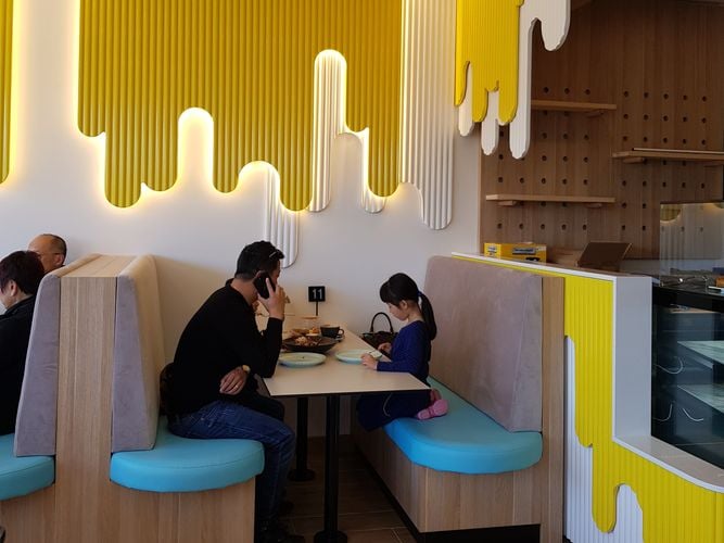 A parent with children at a diner with a wooden dowel panelling accent wall