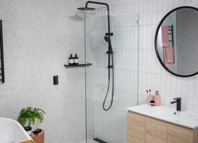 Bathroom with marble wall and white tiled walls with black colour fittings. 