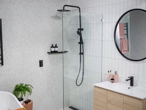 Bathroom with marble wall and white tiled walls with black colour fittings. 