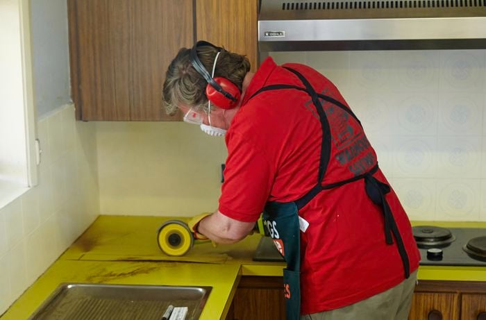 Person using a handsaw on a benchtop.