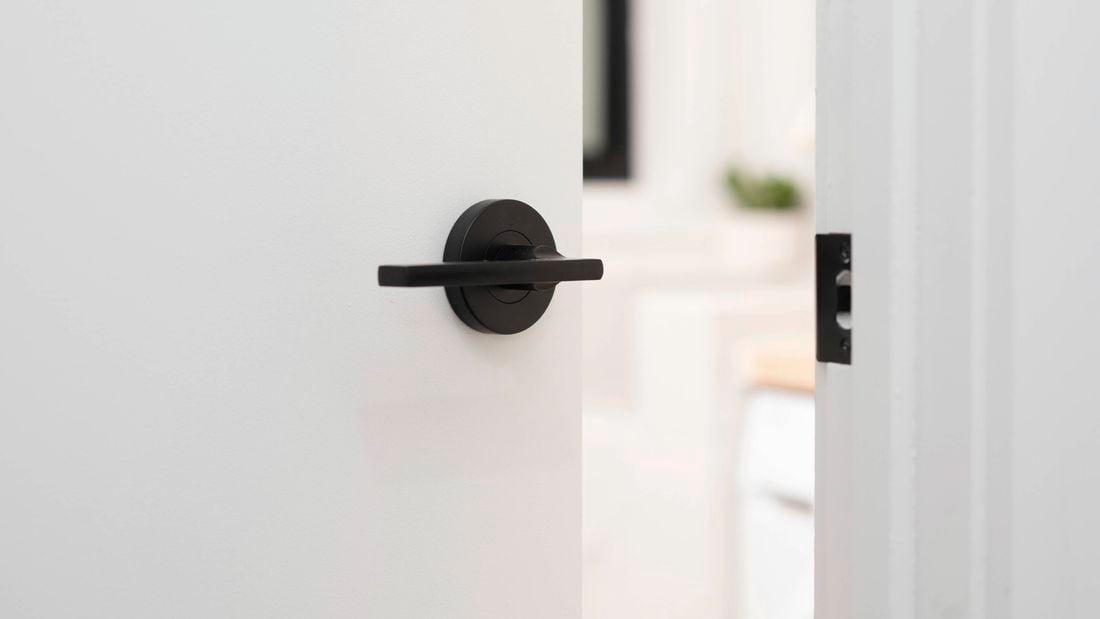 White door with a sleek black handle is partially open