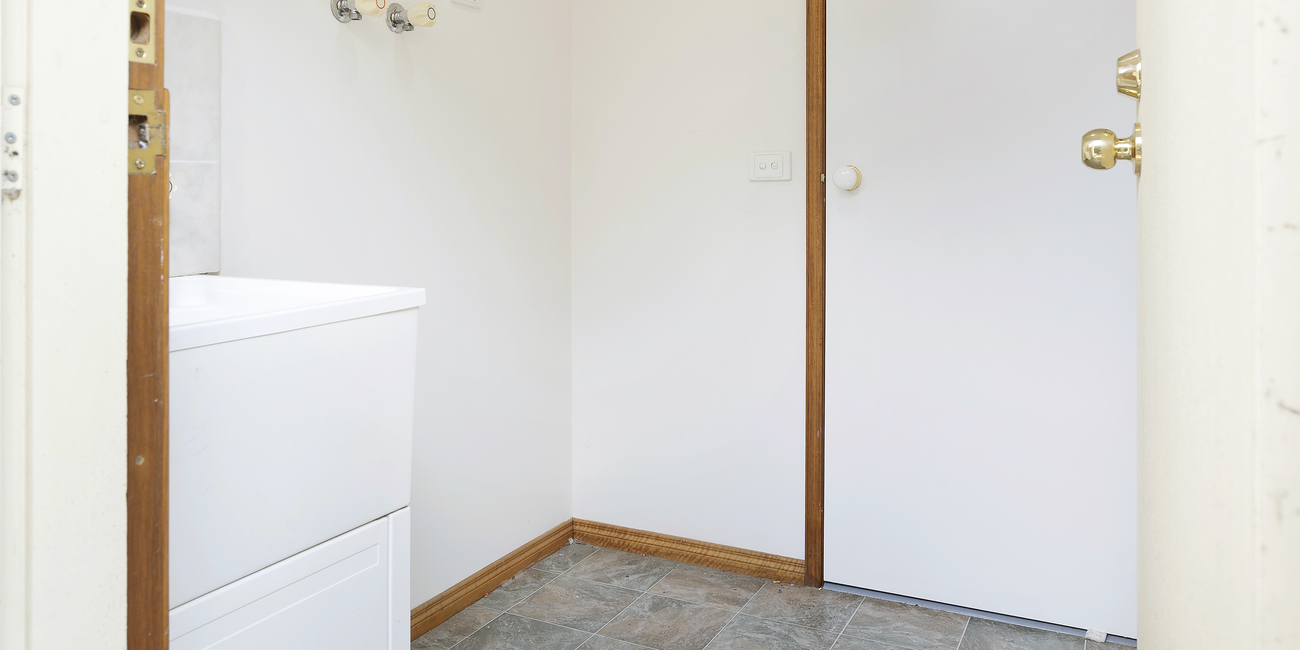 Dated laundry with slate floors and single washing machine.