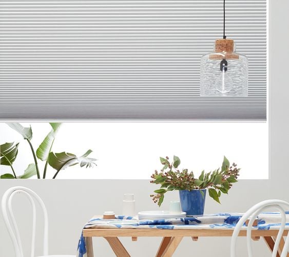 Modern interior with table and chairs in front of a window with white venetian blinds