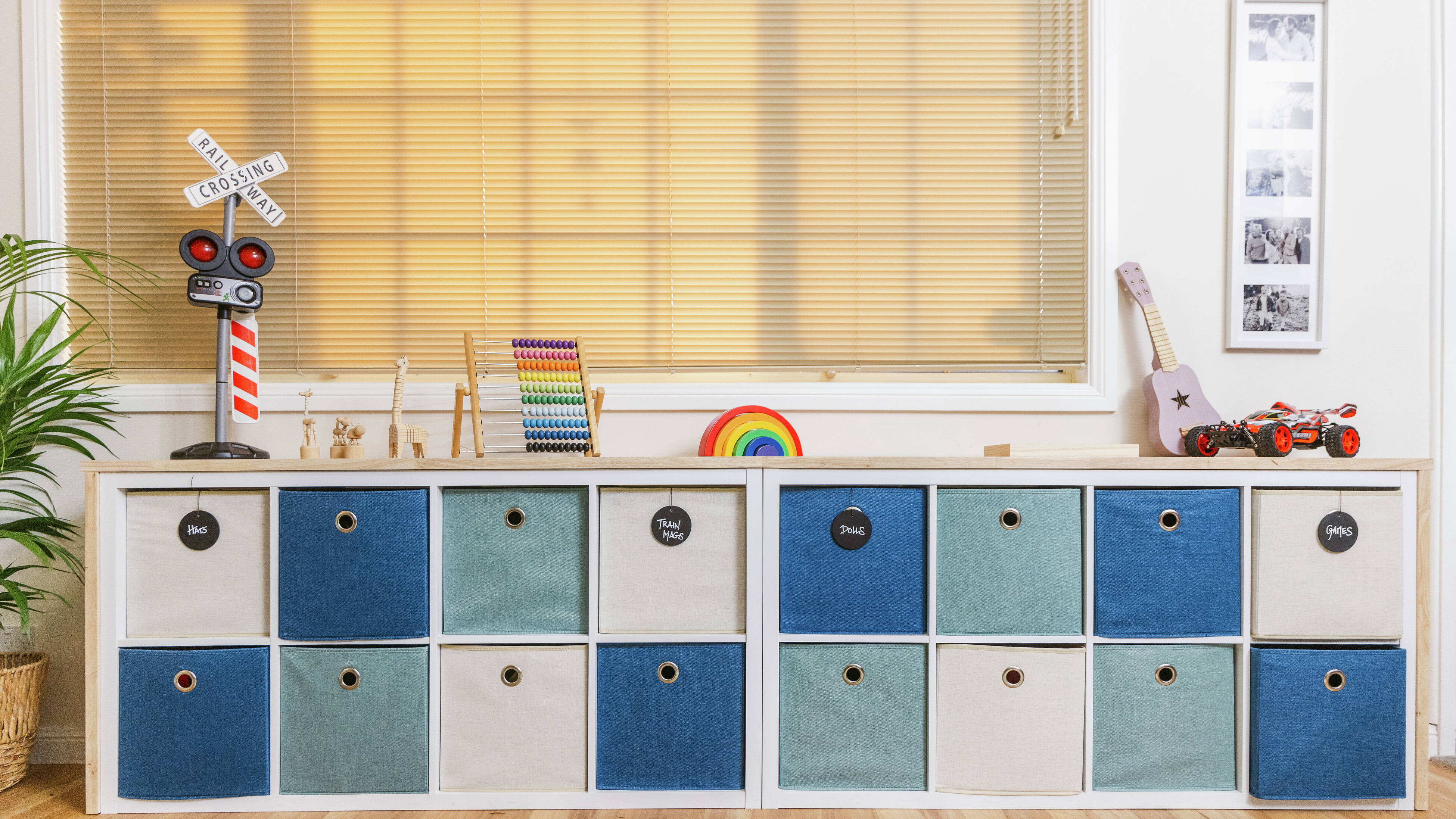 Tidy playroom featuring blue-and-white storage cubbies, neatly arranged toys, and sunlight filtering through a large window.