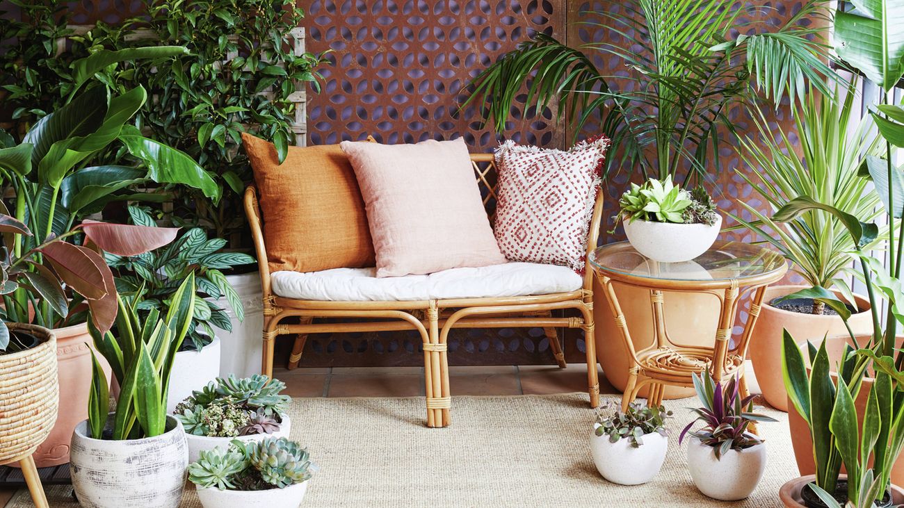 A stylised balcony with leafy greenery, pot plants, a seat and glass-topped table